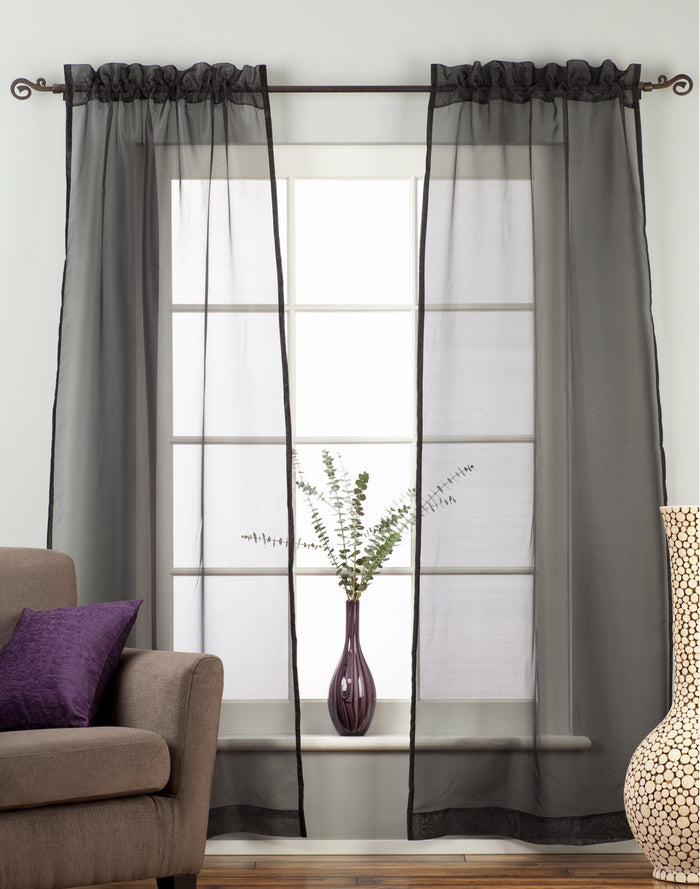 Black sheer tissue rod pocket curtains hung at a window