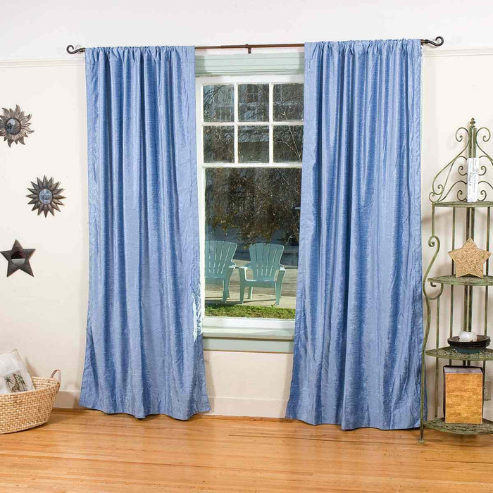Light blue velvet rod pocket curtains hung at a window