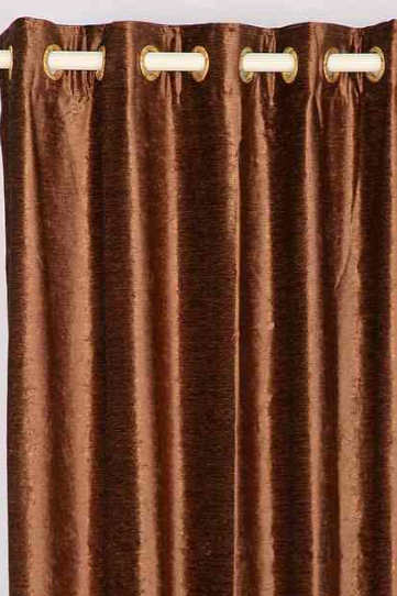 Brown velvet grommet top curtains hung at a window