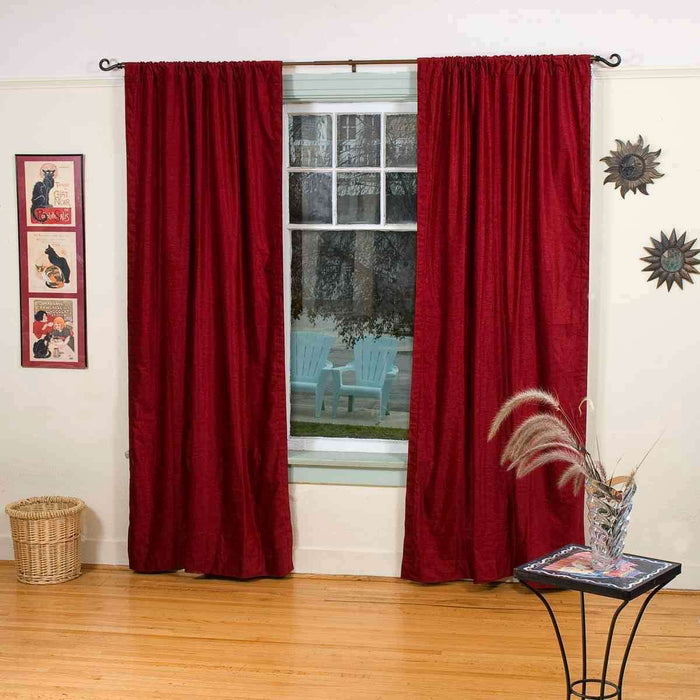 Burgundy velvet rod pocket curtains hung at a window