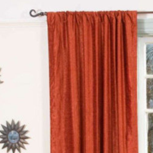 Rust velvet rod pocket curtains hung at a window