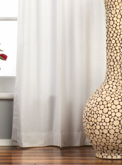 White velvet grommet top curtains hung at a window