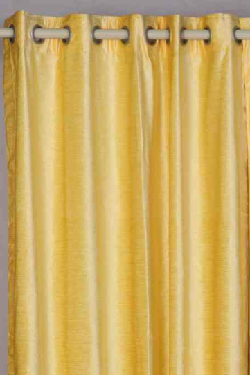 Yellow velvet grommet top curtains hung at a window
